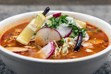 Spicy Pozole stew served loaded with meat and vegetables in a large hearty bowl.
