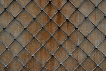 Metal lattice in the form of rhombuses on the background of a concrete wall