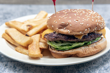 Cheeseburger stacked high with melted cheese and fillings combined with a thick serving of steak fries.
