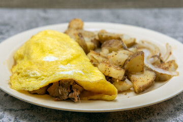 Chili verde pork meat omelette served with seasons roasted potatoes as a traditional Mexican food breakfast.
