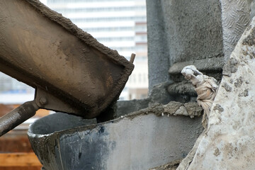 Concrete is poured from a concrete mixer into a metal container on construction site. Cement truck...