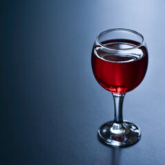 Glass of red wine on a dark blue background.