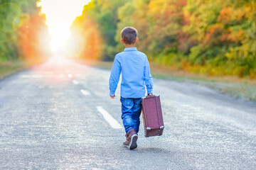 A Happy child with a suitcase on the road in the park travel