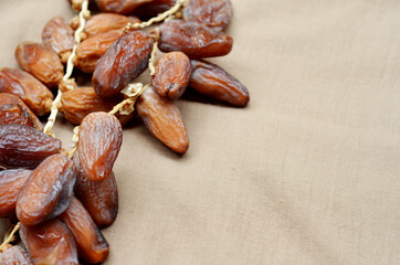 Dates (Phoenix dactylifera) on a wooden bowl on a brown cloth background. food for breaking the fast during Ramadan for Muslims. selective focus
