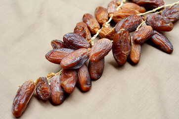 Dates (Phoenix dactylifera) on a wooden bowl on a brown cloth background. food for breaking the fast during Ramadan for Muslims. selective focus