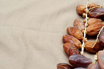 Dates (Phoenix dactylifera) on a wooden bowl on a brown cloth background. food for breaking the fast during Ramadan for Muslims. selective focus