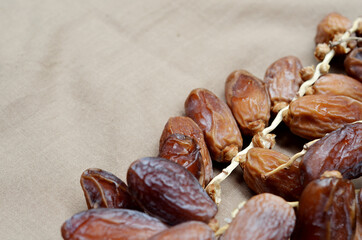 Dates (Phoenix dactylifera) on a wooden bowl on a brown cloth background. food for breaking the fast during Ramadan for Muslims. selective focus