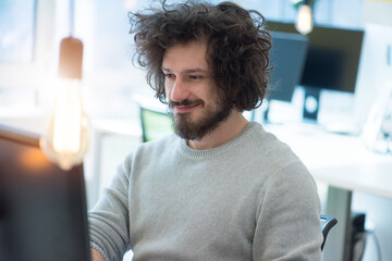 Young man working on his computer in co-creative space.  Working on new creative digital projects...