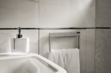 Detailaufnahme eines Badezimmers. Angefertigter strassbesetzter Handtuchhalter, Handtuchring mit  weißem Handtuch. Daneben ein Seifenspender, der ebenfalls mit Strass verziert ist - obrazy, fototapety, plakaty