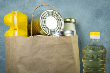 Canned food, milk, eggs and oil in bottle in paper bag. Home delivery of groceries. Helping poor and elderly in isolation. Basic set of goods for consumption.