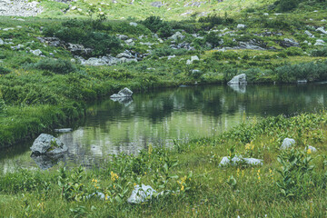 Obraz premium Mountain lake with grassy banks and boulders