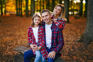 Fototapeta na wymiar photo of a wonderful family in the autumn forest on a bench
