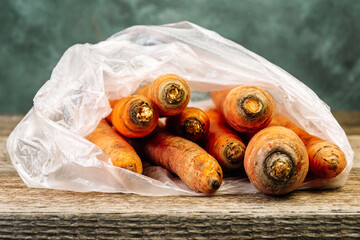 Carrots in transparent bag on wooden table.