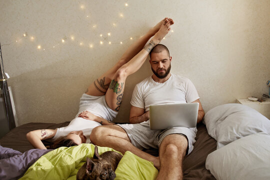 Man working with his laptop computer while his lovely woman relaxing nearby