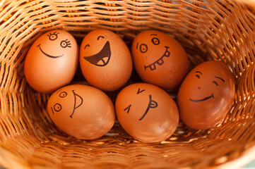 Stack of eggs with hand drawn faces on straw basket, easter preparation, holiday mood concepts