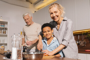 Happy multiracial family standing at the table while cooking at the kitchen