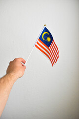 Hand holding hand flag of Malaysia