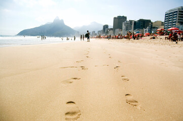 Copacabana beach rio de janeiro brazil. Sunny summer, sand with footprints, humped in the background and people enjoying the weekend on the beach with the extended holiday
