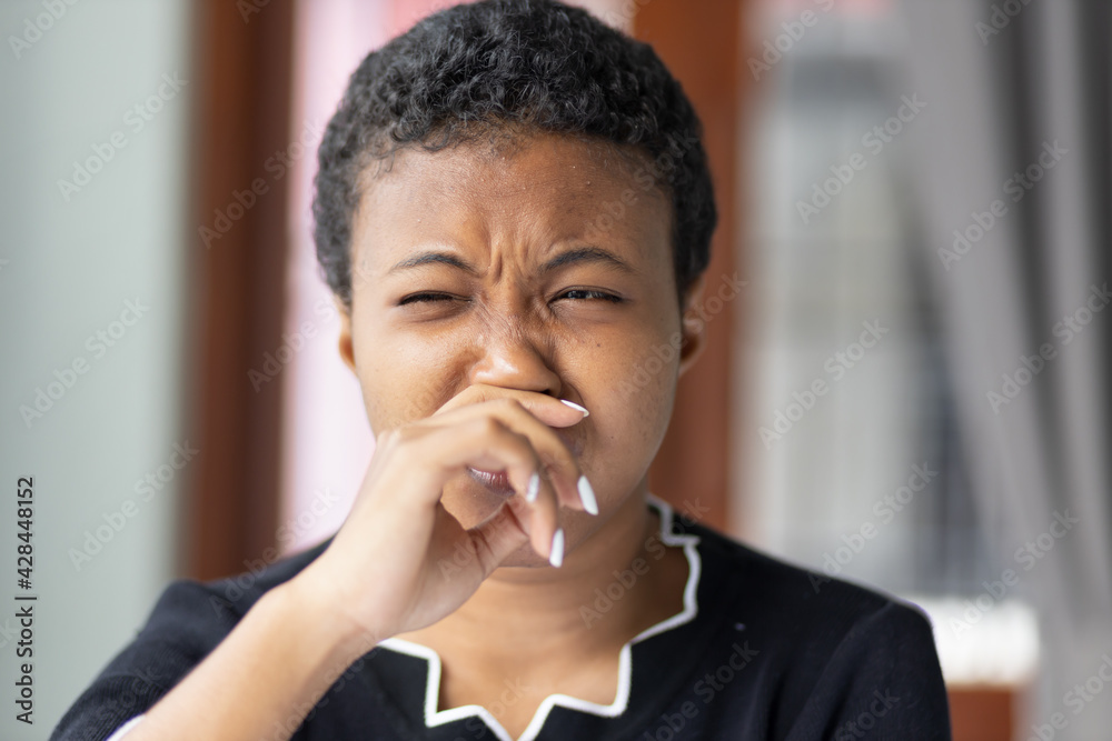 Wall mural african woman having runny nose or covering her nose for bad smell, concept of stink thing, bad brea