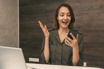 Portrait of a happy young girl who looks into the phone. Surprised young woman with phone 