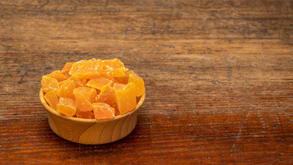 dried mango fruit diced - a small wooden bowl against rustic weathered wood