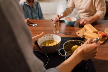 Obraz na płótnie Canvas Woman pouring soup into the plates while having dinner