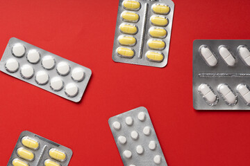 Yellow pills on red background, top view. Different medicines, tablets, medicine capsules. Medicine concept, background. Text place