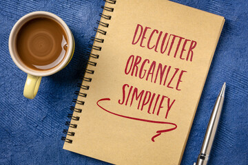 Declutter, organize, simplify. Motivational handwriting in a spiral notebook with a cup of coffee. Business, productivity, lifestyle and personal development concept.