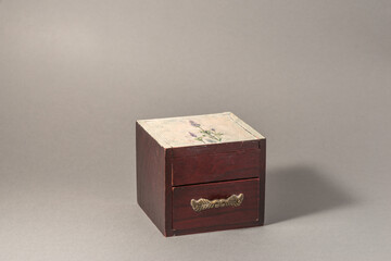 Brown wooden box with closed drawer with gold decoration handle on jewellery.