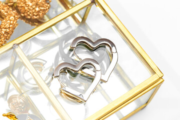 silver heart shaped earrings on glass jewelry box .