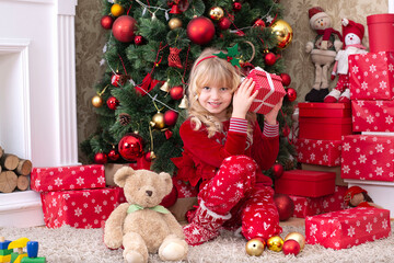 Little girl with  christmas  gifts in front of the Christmas tree