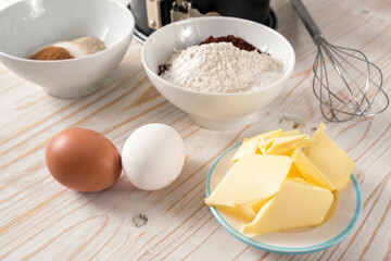 Butter, eggs, flour and sugar, ingredients to bake a cake on a wooden table, selected focus