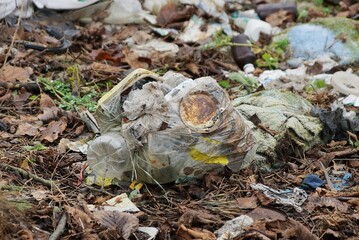 gray bag with trash lies on the ground in brown fallen leaves in nature