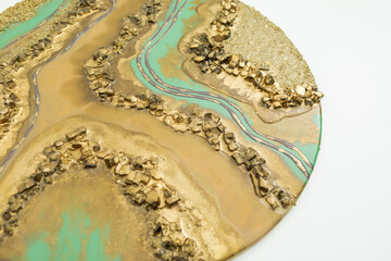 Resin art painting with golden colors and glass on white.
