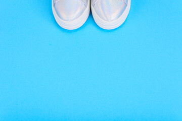 Silver sneakers on a blue background with place for text