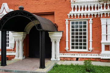 entrance to a beautiful red and white orthodox church, white carved columns and window decorations, red brick walls