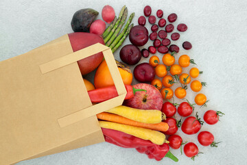 Immune boosting fruit & vegetables for good health high in lycopene, anthocyanins, antioxidants, vitamins, minerals & dietary fibre. In a paper carrier bag and loose on mottled grey background.  