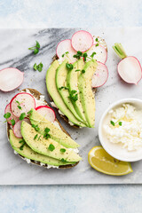 Sandwiches with avocado, radish, micro greens and cream cheese on a marble board. Healthly food. Top view