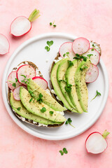 Sandwiches with avocado, radish, micro greens and cream cheese on a white plate. Healthly food. Top view