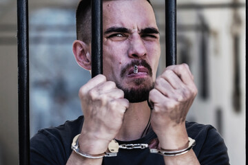 Handcuffed man smoking cigarette imprisoned for crime, punished for serious villainy. Arrest,...