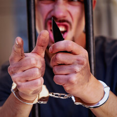 Portrait of handcuffed man with a knife imprisoned for crime, punished for serious villainy....