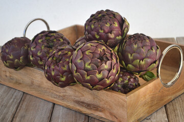 Obraz premium Artichoke. Fresh purple artichokes in wooden box. Harvest concept.