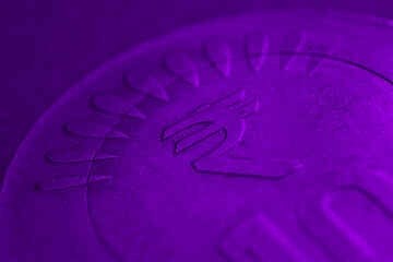 Translation: rupee. Fragment of Indian 10 rupee coin with a national currency symbol. Very dark indigo background or wallpaper. Deep violet tinted backdrop about money, economy or finance of India