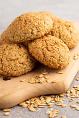 In the foreground is a blurred image of oatmeal cookies on a wooden board against a gray background.