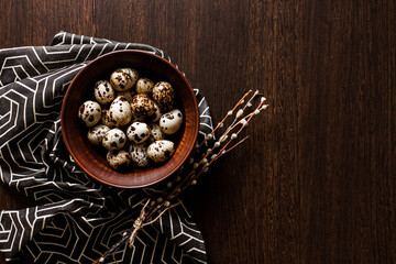 Quail eggs in a clay plate on a dark background