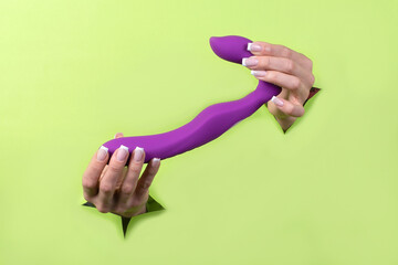 A Erotic toy for pleasure in the hands of a woman on a green background. A masturbation device for...