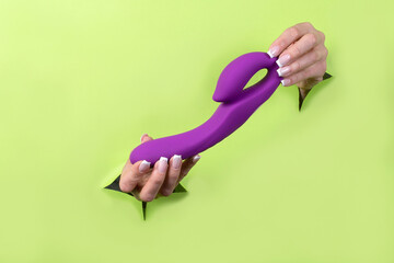 A Erotic toy for pleasure in the hands of a woman on a green background. A masturbation device for...