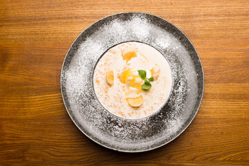 Top view photo of beautiful plate with oatmeal and banana decorated with mint over wooden table in restaurant