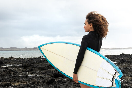 Multiracial surfer young woman standing by the sea