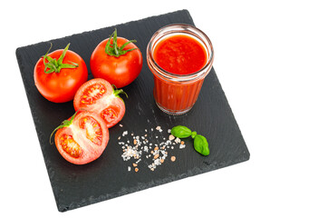 Glass of tomato juice, ripe red tomatoes on black stone tray
